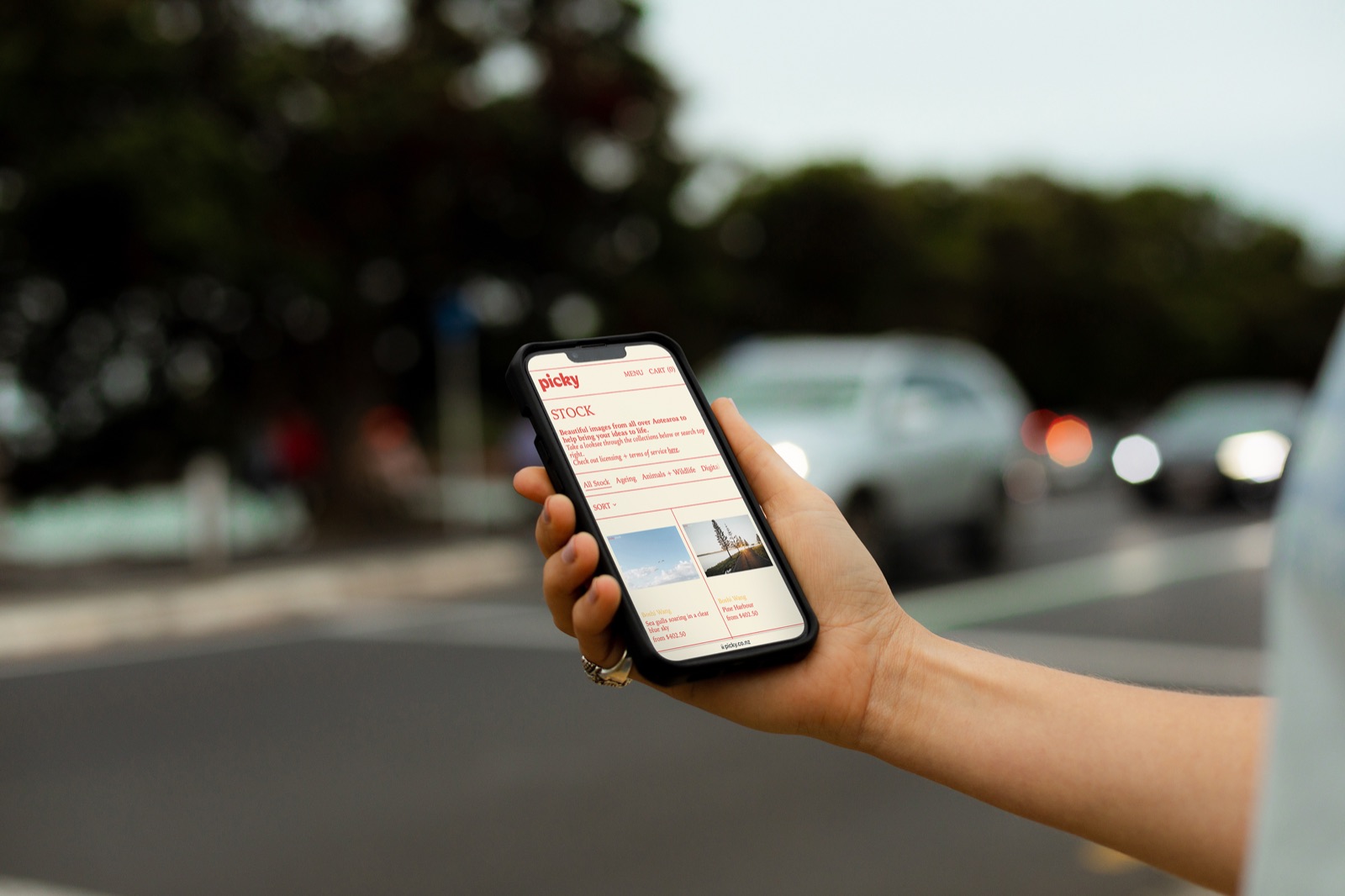 Woman browsing the Picky stock photo library on her phone near a busy street