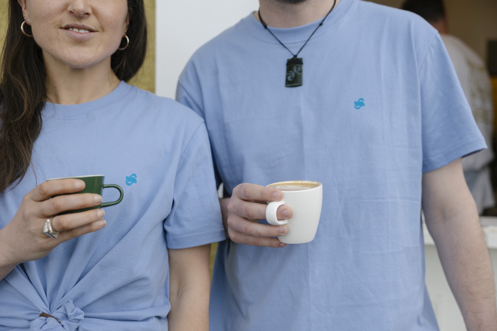 Two people at a Stretchy meetup holding coffee mugs, wearing blue Stretchy branded t-shirts